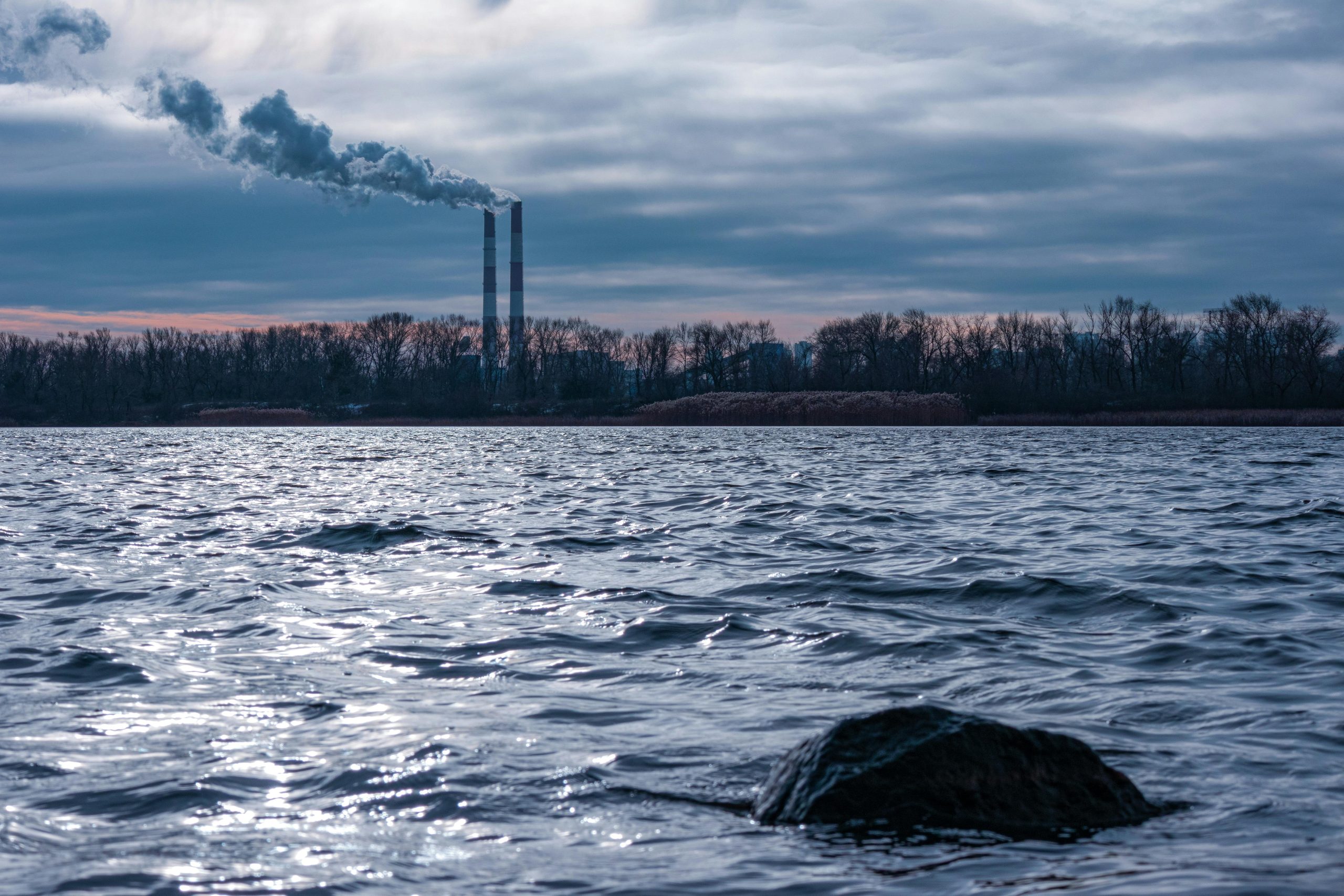 factory smokestacks over rippling water